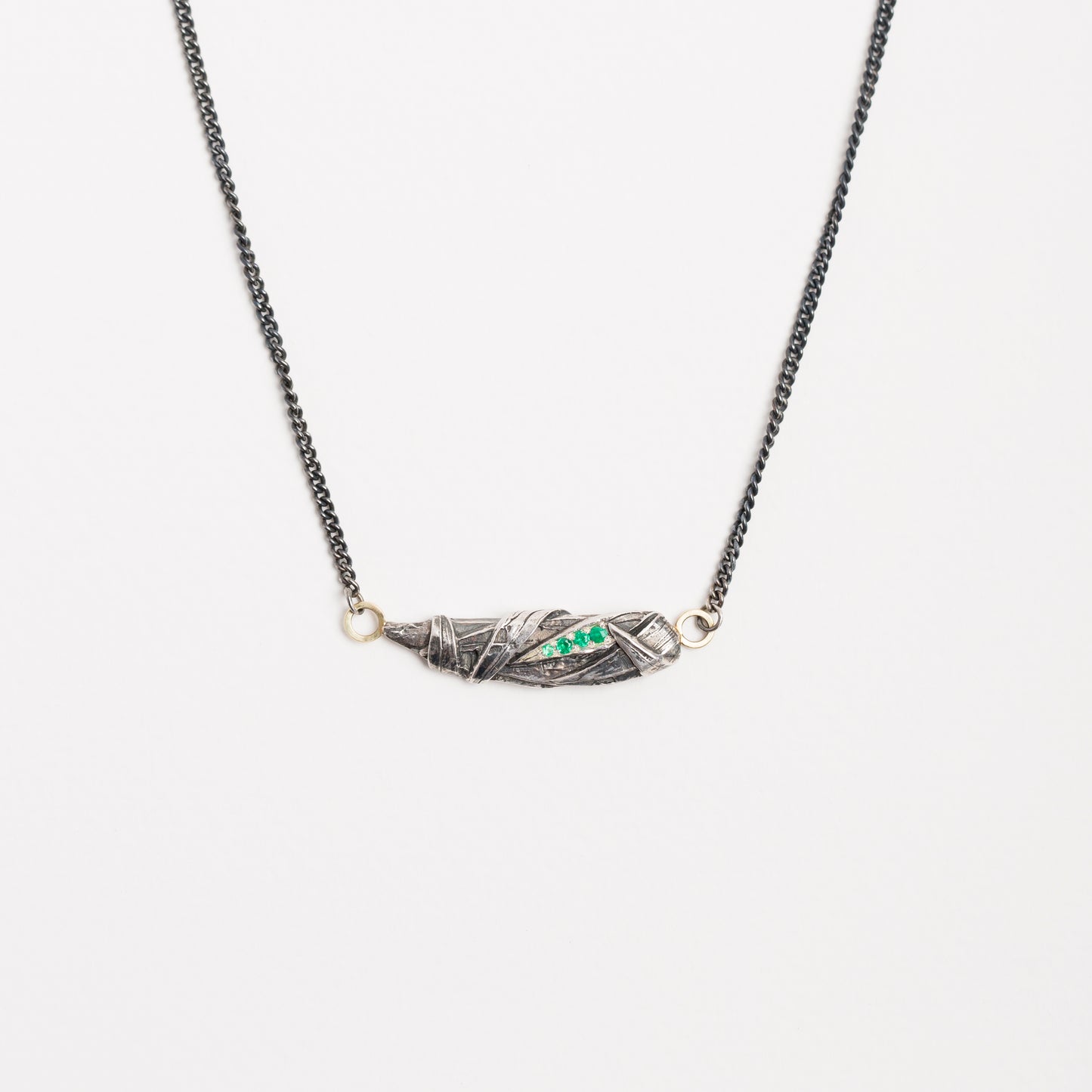 Woven pendant with emeralds