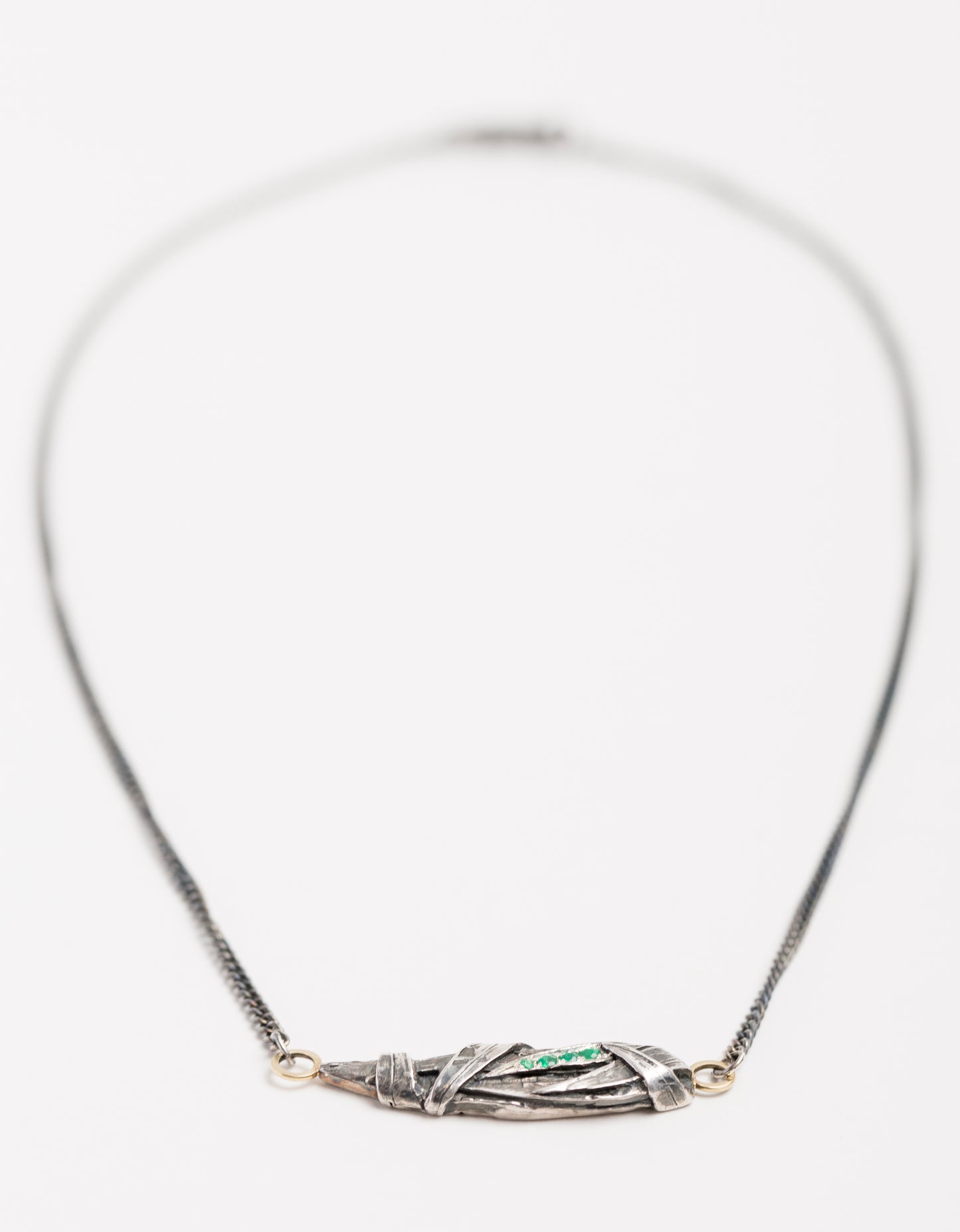 Woven pendant with emeralds