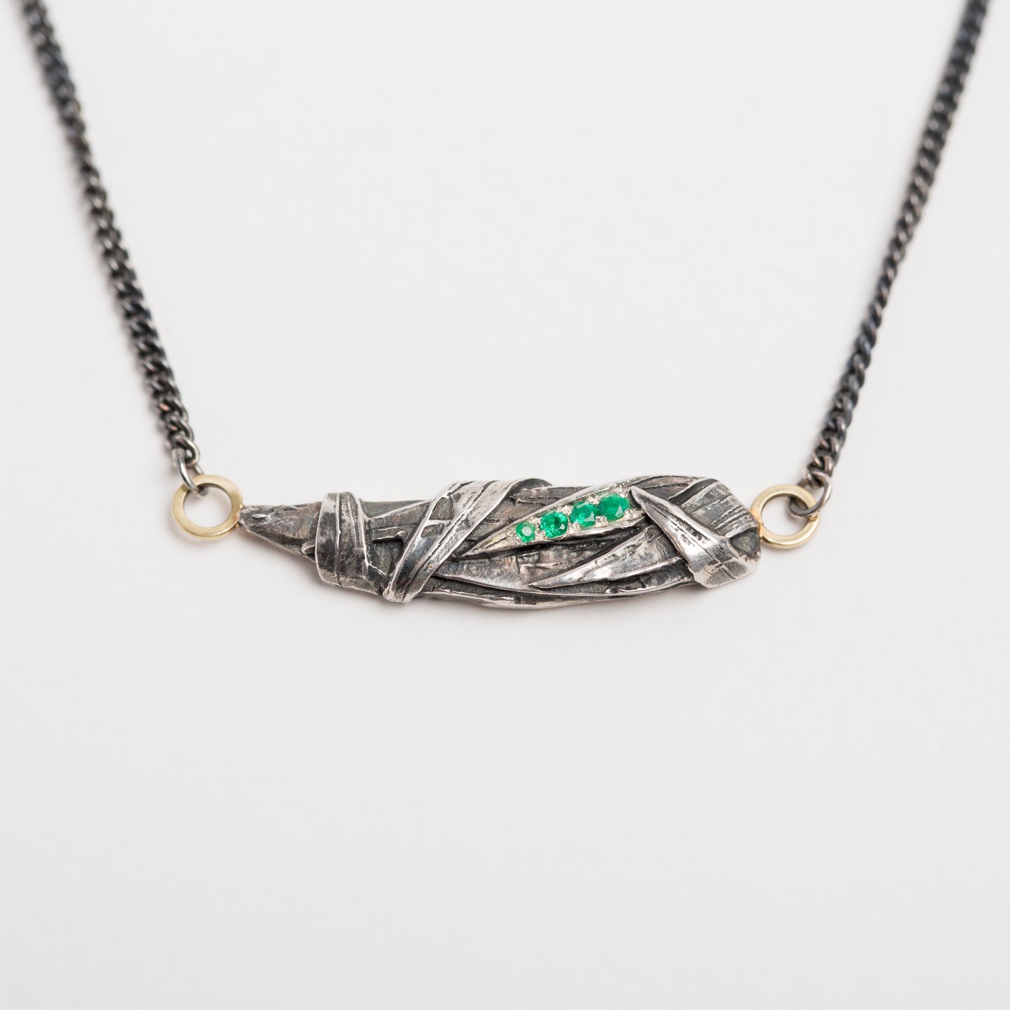 Woven pendant with emeralds